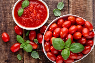 Tabaktaki taze domatesler ahşap masada. Domates arka planı, sağlıklı sebze ve fesleğen yaprakları..