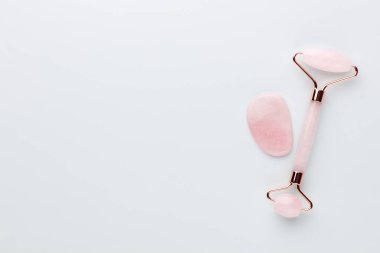 Gua Sha yüz masajı aletleri ve salatalık. Pastel arka planda kuvars yeşim silindiri. Evde yaş, kaldırma ve tonlama karşıtı tedavi. 