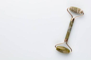 Gua Sha yüz masajı aletleri ve salatalık. Pastel arka planda kuvars yeşim silindiri. Evde yaş, kaldırma ve tonlama karşıtı tedavi. 