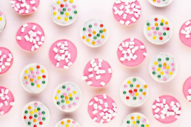Beyaz arka planda çok renkli, güzel dekore edilmiş muffinler..
