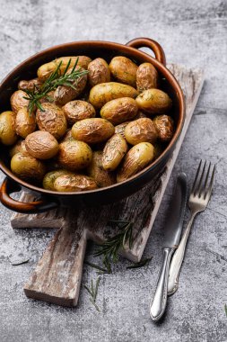 Kavrulmuş patatesle dolu tava sade ahşap masada atılıyor. İçlerinde çiğ patates, biberiye, dereotu, tuz, biber ve sarımsak var.. 