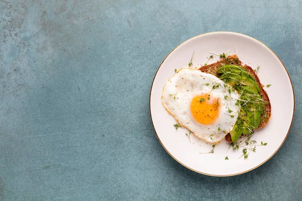 Keto kahvaltısı sahanda yumurta, avokado ve ekmek. Keto diyet kavramı.