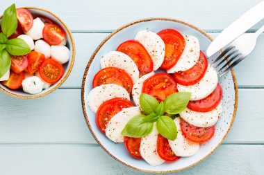 Domates, mozzarella peyniri, fesleğen ve baharatlar gri tahtada. İtalyan geleneksel Caprese salata malzemeleri. Akdeniz yemekleri.