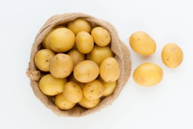 Ahşap arka planda taze çiğ patates çuvalı.