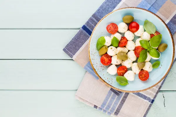 Kiraz domatesleri, mozzarella peyniri, fesleğen ve baharatlar gri tahta üzerinde. İtalyan geleneksel Caprese salata malzemeleri. Akdeniz yemekleri.
