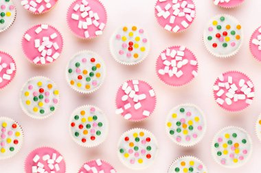 Beyaz arka planda çok renkli, güzel dekore edilmiş muffinler..