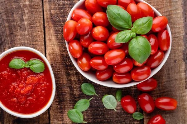 Tabaktaki taze domatesler ahşap masada. Domates arka planı, sağlıklı sebze ve fesleğen yaprakları..