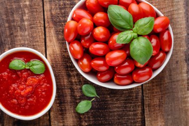 Tabaktaki taze domatesler ahşap masada. Domates arka planı, sağlıklı sebze ve fesleğen yaprakları..