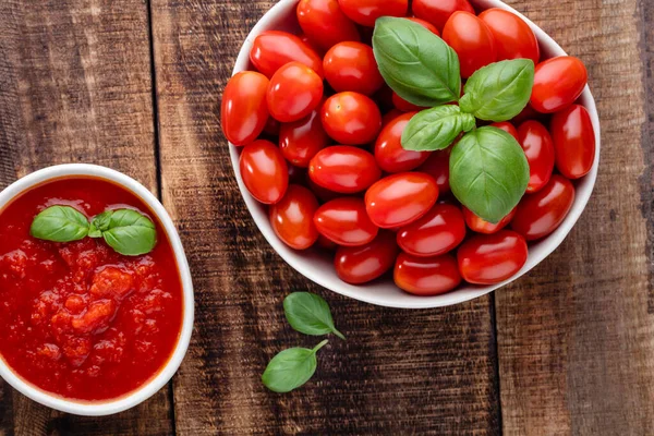 Tabaktaki taze domatesler ahşap masada. Domates arka planı, sağlıklı sebze ve fesleğen yaprakları..
