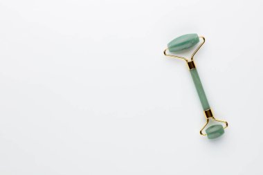 Gua Sha yüz masajı aletleri ve salatalık. Pastel arka planda kuvars yeşim silindiri. Evde yaş, kaldırma ve tonlama karşıtı tedavi. 