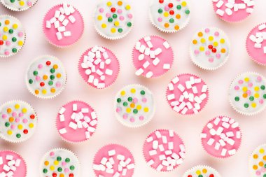 Beyaz arka planda çok renkli, güzel dekore edilmiş muffinler..