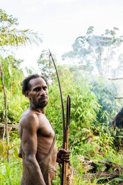 NDONESIA, NEW GUINEA, IRIAN JAYA, ONNI VILLAGE - 27 Haziran 2012: Korowai kabilesinden Papuan. Korowai kombai (Kolufo) doğal orman arka planında yay ve oklarla