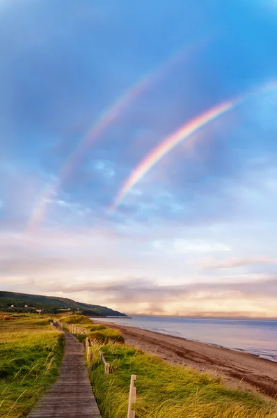 Alba in spiaggia con doppio arcobaleno — Foto Stock