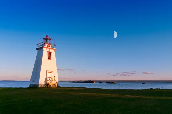 Lighthouse in the light from moon and sun — Stock Photo, Image