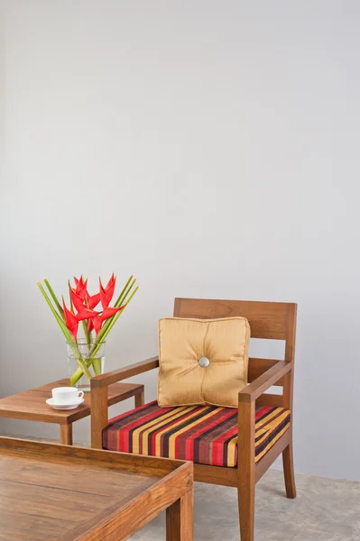 Beige upholstered chair with side table and flowers — Stock Photo, Image