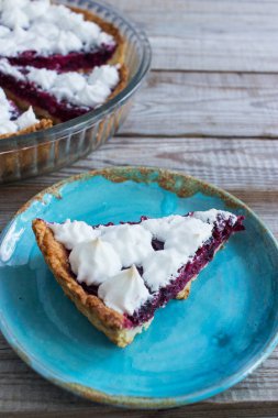 Mavi tabak dilimi küçük kremalı böğürtlen tartı ahşap masa.