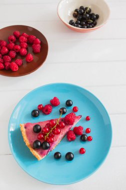 Kama Frenk üzümü tart mavi kahverengi tabak kase Beyaz ahşap arka plan dekore edilmiştir..