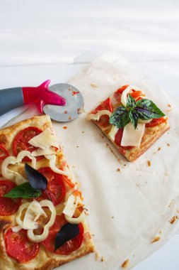 Kare pastırmalı pizza kitabı beyaz ahşap arka plan seçici odak.