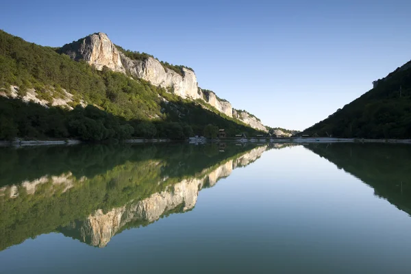 Rocky and green mountains reflect by the lake — Stock Photo, Image