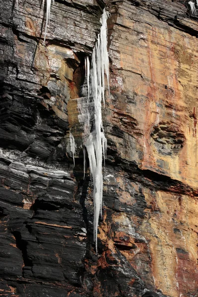 Dripping frozen icicles on a cliff face — Stock Photo, Image