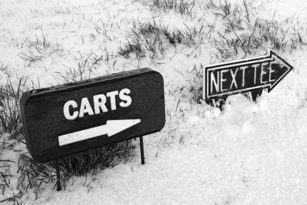 Carrello e successivo cartello tee su un campo da golf innevato — Foto Stock