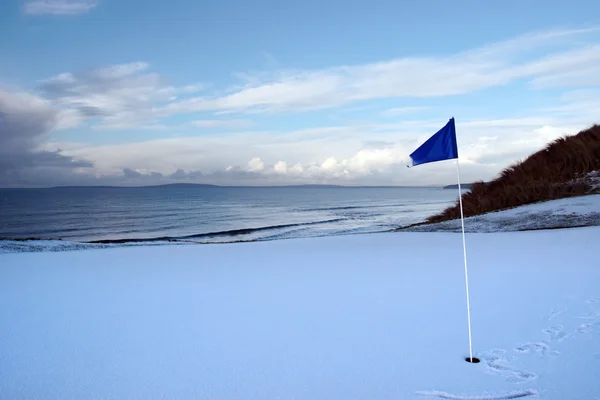 Campo de golf verde con nieve y bandera azul — Foto de Stock