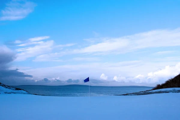 高尔夫绿色与冬天的雪和蓝旗 — 图库照片