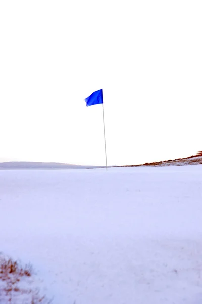 Links campo de golfe verde com neve e bandeira azul — Fotografia de Stock