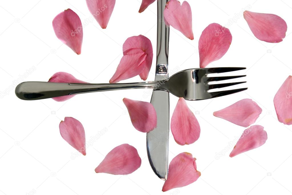 crossed silver fork and knife isolated with rose petals