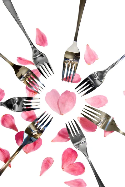 Tenedores de plata y oro que rodean la forma del corazón con pétalos de rosa —  Fotos de Stock