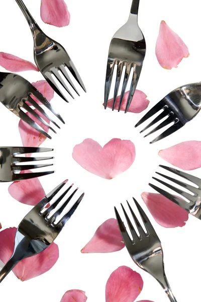 Silver forks surrounding heart shape and rose petals — Stok fotoğraf