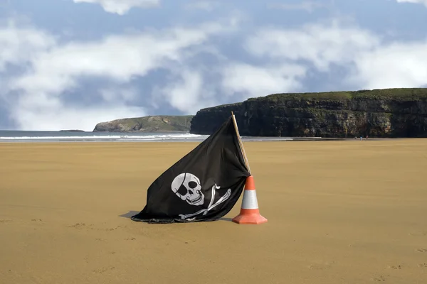 Sandy beach with jolly roger flag — Stock Photo, Image