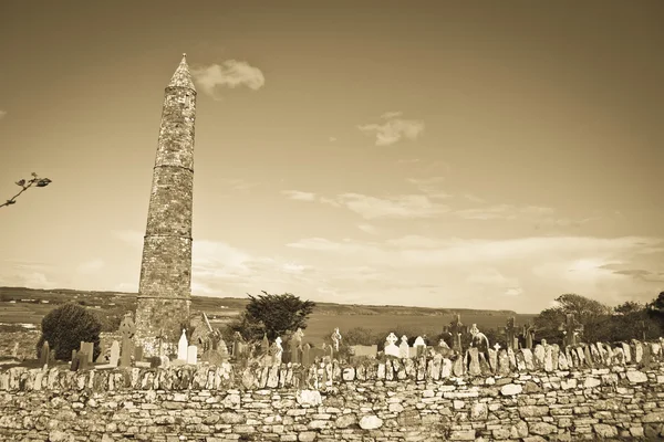 Древняя круглая башня и кельтское кладбище в сепии — стоковое фото