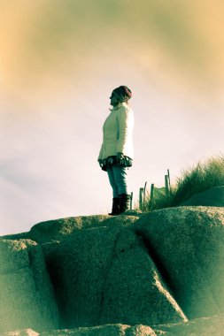 woman looking out to sea a top of rock formation