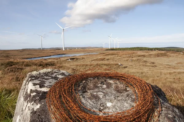 Barbed wire on a rock with wind turbines — Stock Photo, Image