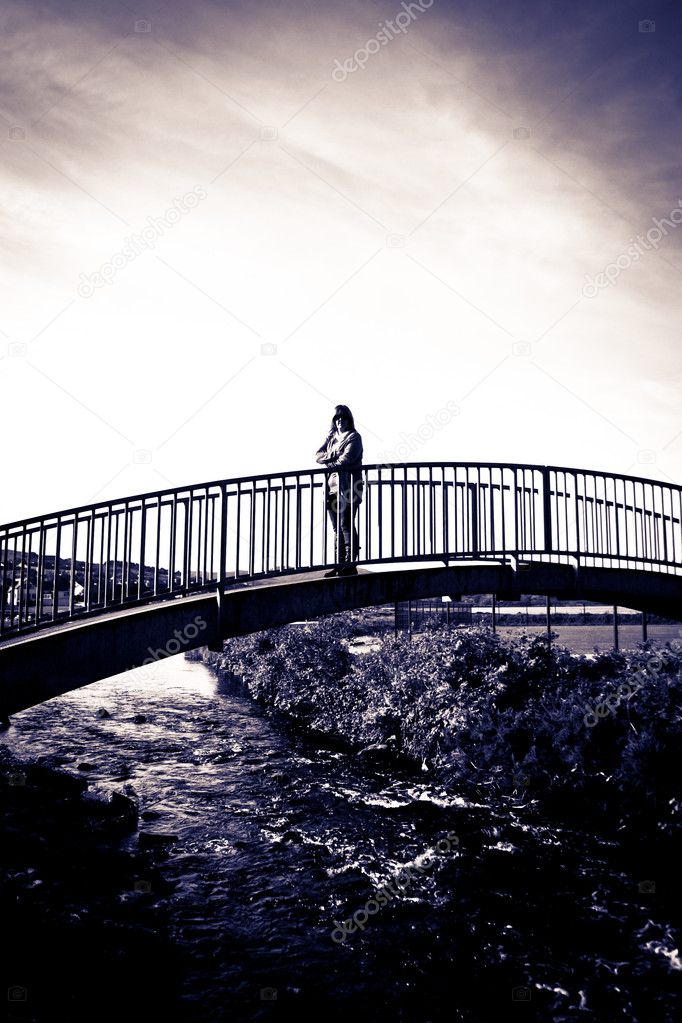 Woman silhouetted strolling on a modern bridge
