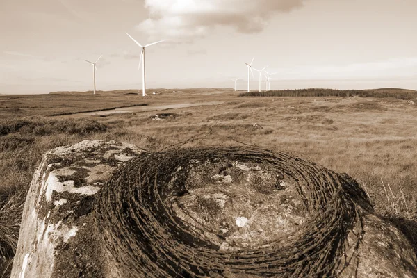 Sepia barbed wire on a rock with wind turbines — Stock Photo, Image