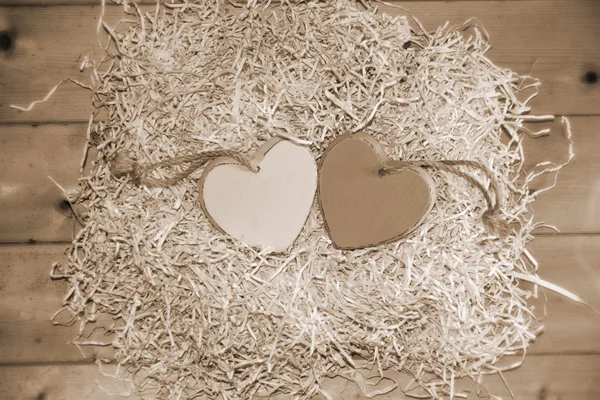 Dois corações de sépia de madeira no ninho — Fotografia de Stock