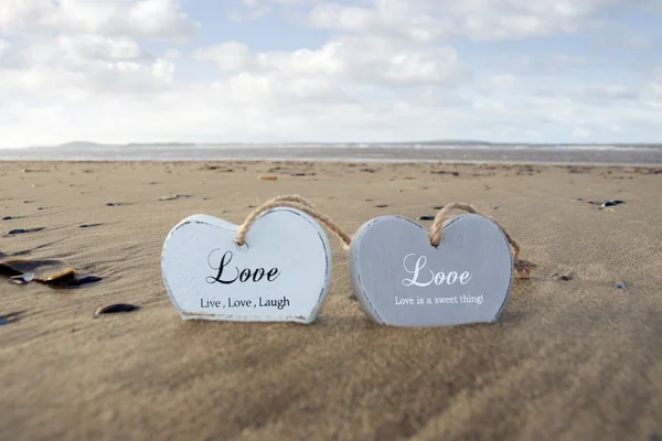 Casal de corações de amor de madeira inscritos na areia — Fotografia de Stock