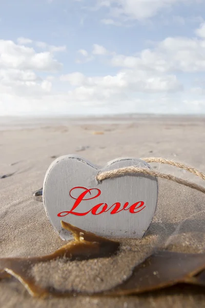 Inscribed wooden love heart in the sand — Stock Photo, Image