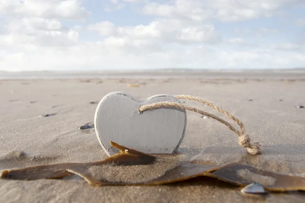 Corazón de amor de madera en la arena — Foto de Stock