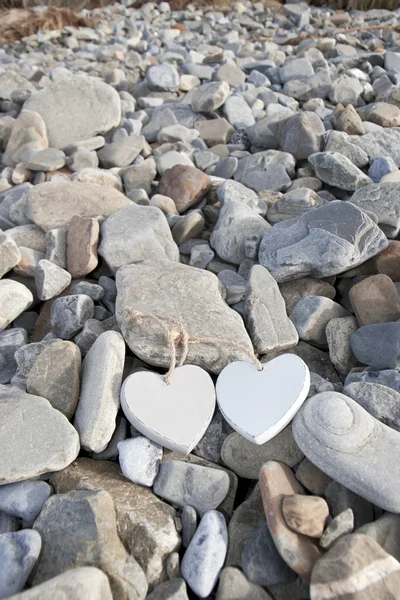 Dois corações de madeira em uma praia rochosa — Fotografia de Stock
