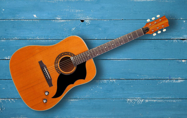Musical instrument - Top view vintage western acoustic guitar on a blie wood background