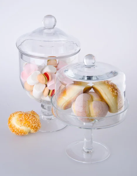Donut, bun, cookie & glass jar on background — Stock Photo, Image