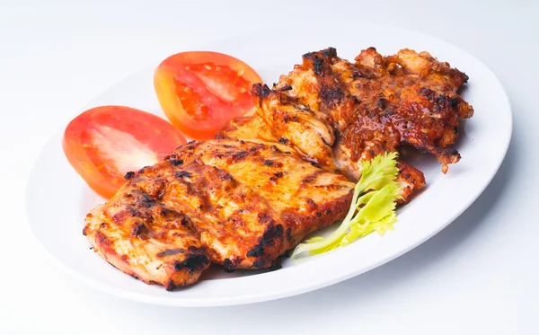 Grilled chicken on a white plate with vegetables on background. — Stock Photo, Image