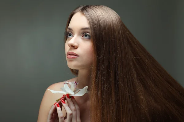 Gyönyörű lány, hosszú haj, egy szürke háttér, érzelmek, kozmetikai portréja — Stock Fotó
