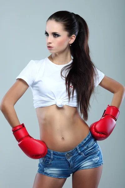 Bela menina boxe sexual, fitness, em um fundo cinza — Fotografia de Stock