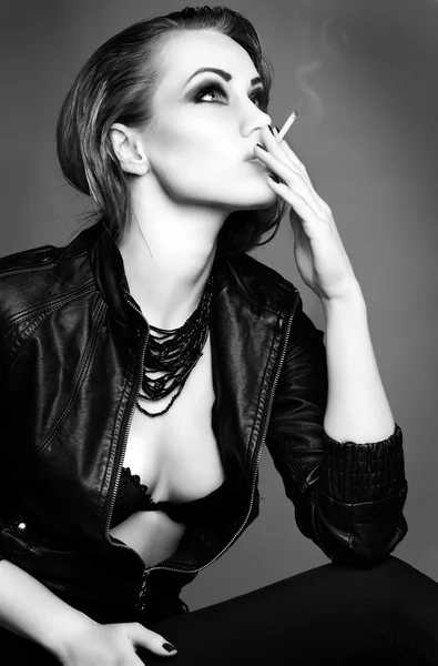Un retrato de hermosa chica pelirroja sexual está en una chaqueta de cuero negro, fumando un cigarrillo —  Fotos de Stock