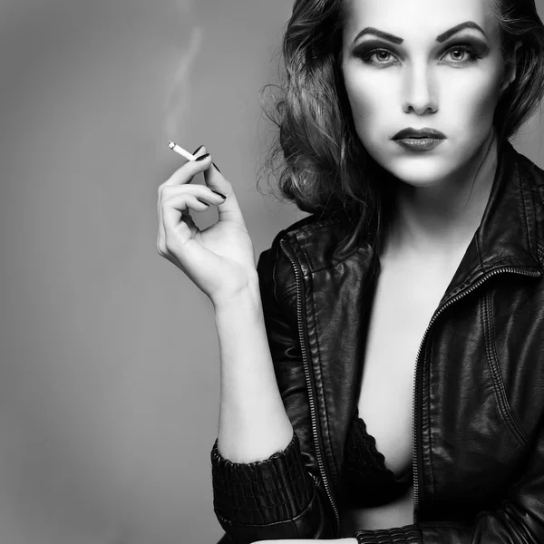 Ένα πορτρέτο του όμορφη σεξουαλική redheaded κορίτσι είναι σε ένα μαύρο δερμάτινο μπουφάν, καπνίζει ένα τσιγάρο — Φωτογραφία Αρχείου