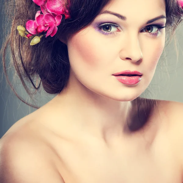 Retrato de hermosa morena sexual con orquídeas rosadas en pelos. emociones, cosméticos —  Fotos de Stock